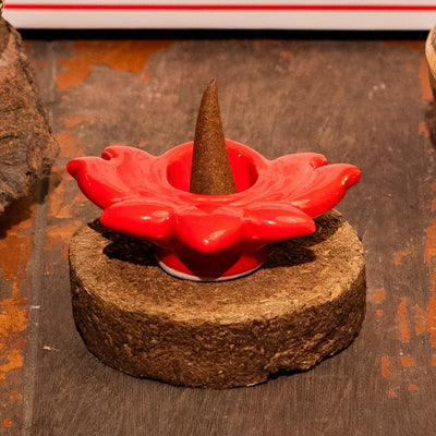 Red flower-shaped incense holder with a cone on a wooden base